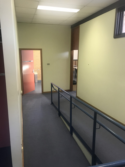 The room is at the end of the corridor on the right